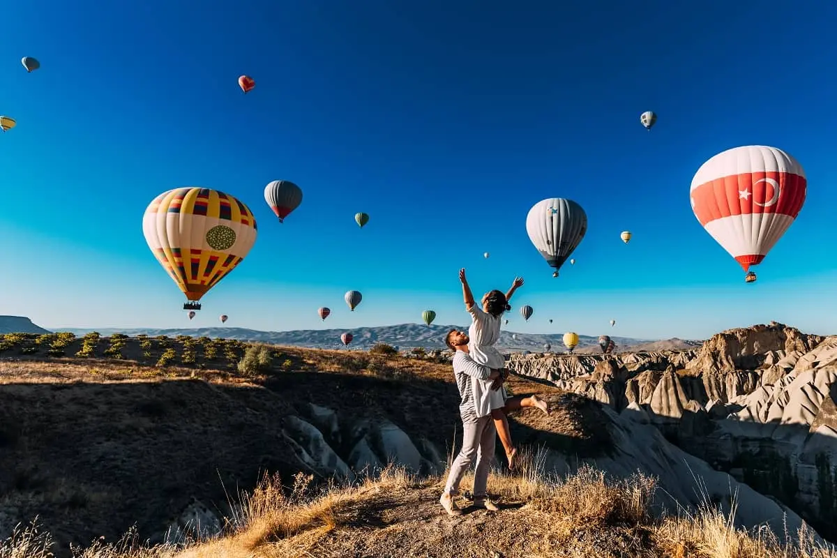 Travelers beneath balloons among the fairy chimneys